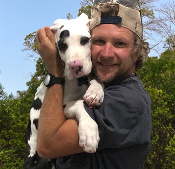 Dr. Ellis holding black and white dog close to his face
